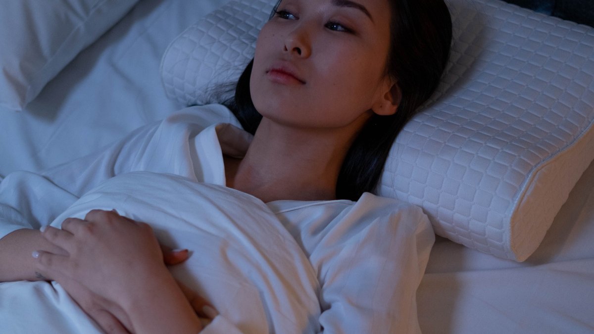 Mulher acordada na cama durante a noite